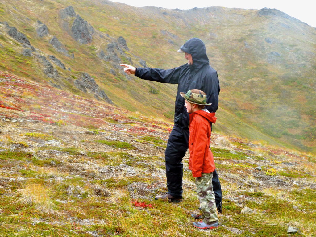 an adult and a child hiking in the mountains in Alaska