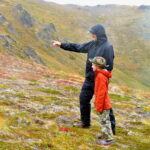 an adult and a child hiking in the mountains in Alaska